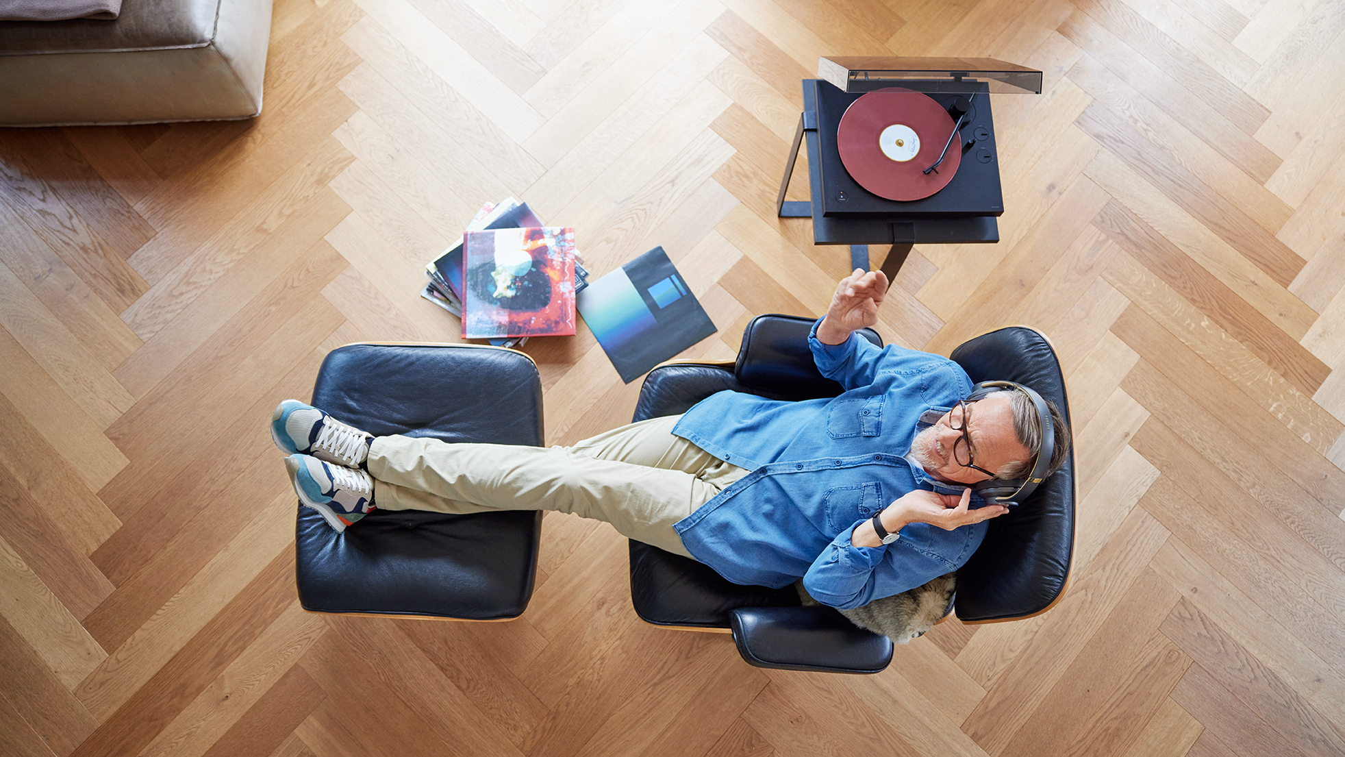 Mann sitzt im Sessel, hat die Füße hochgelegt und telefoniert mit seinem Smartphone